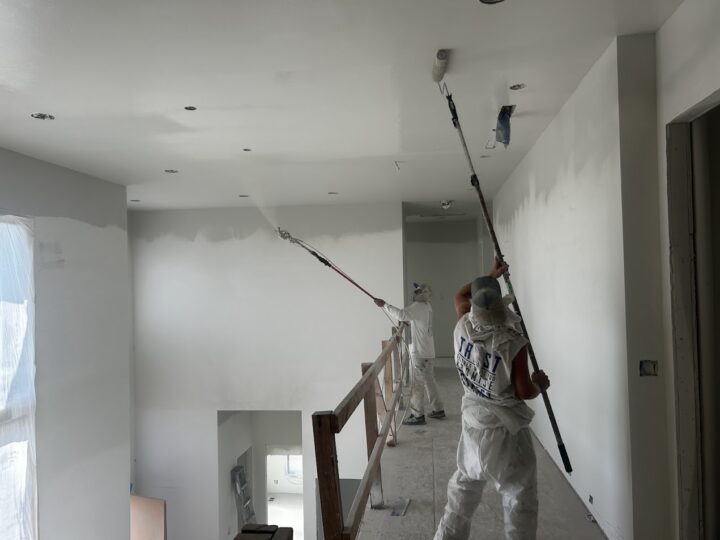 In June 2025, two Wheeler painters use rollers to paint the walls and ceiling of an unfinished interior.