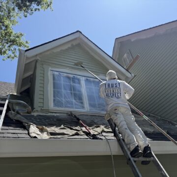A painter with Pearl Painters paints the exterior of a Kearns house near a second-story window covered in plastic sheeting, June 2025.