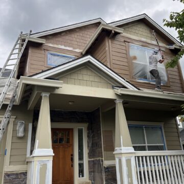 In June 2025, a painter from Pearl Painters uses a roller to paint the upper exterior of an Emory house in Portland, with windows and trim covered for protection.