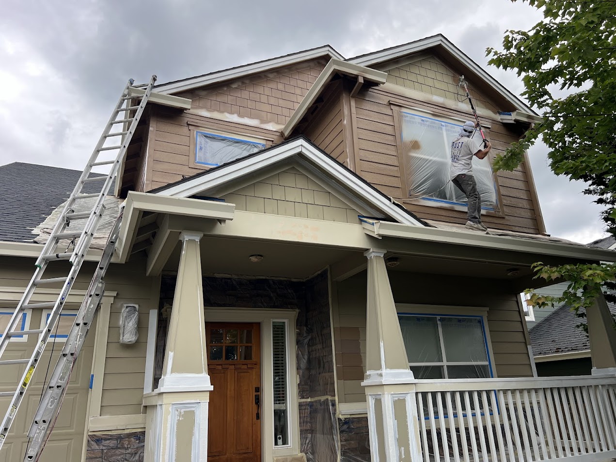 In June 2025, a painter from Pearl Painters uses a roller to paint the upper exterior of an Emory house in Portland, with windows and trim covered for protection.