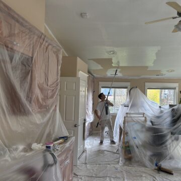 A man is painting a room in a house using professional painting services by Pearl Painters.