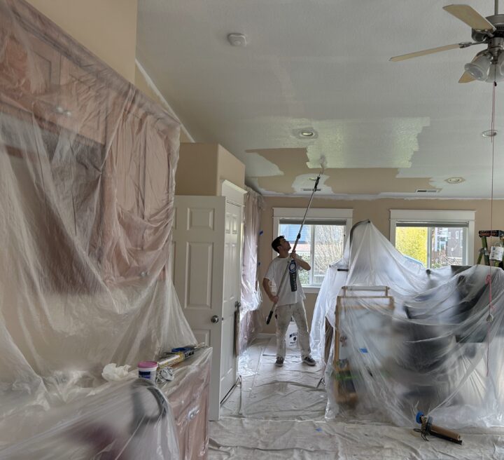 A man is painting a room in a house using professional painting services by Pearl Painters.