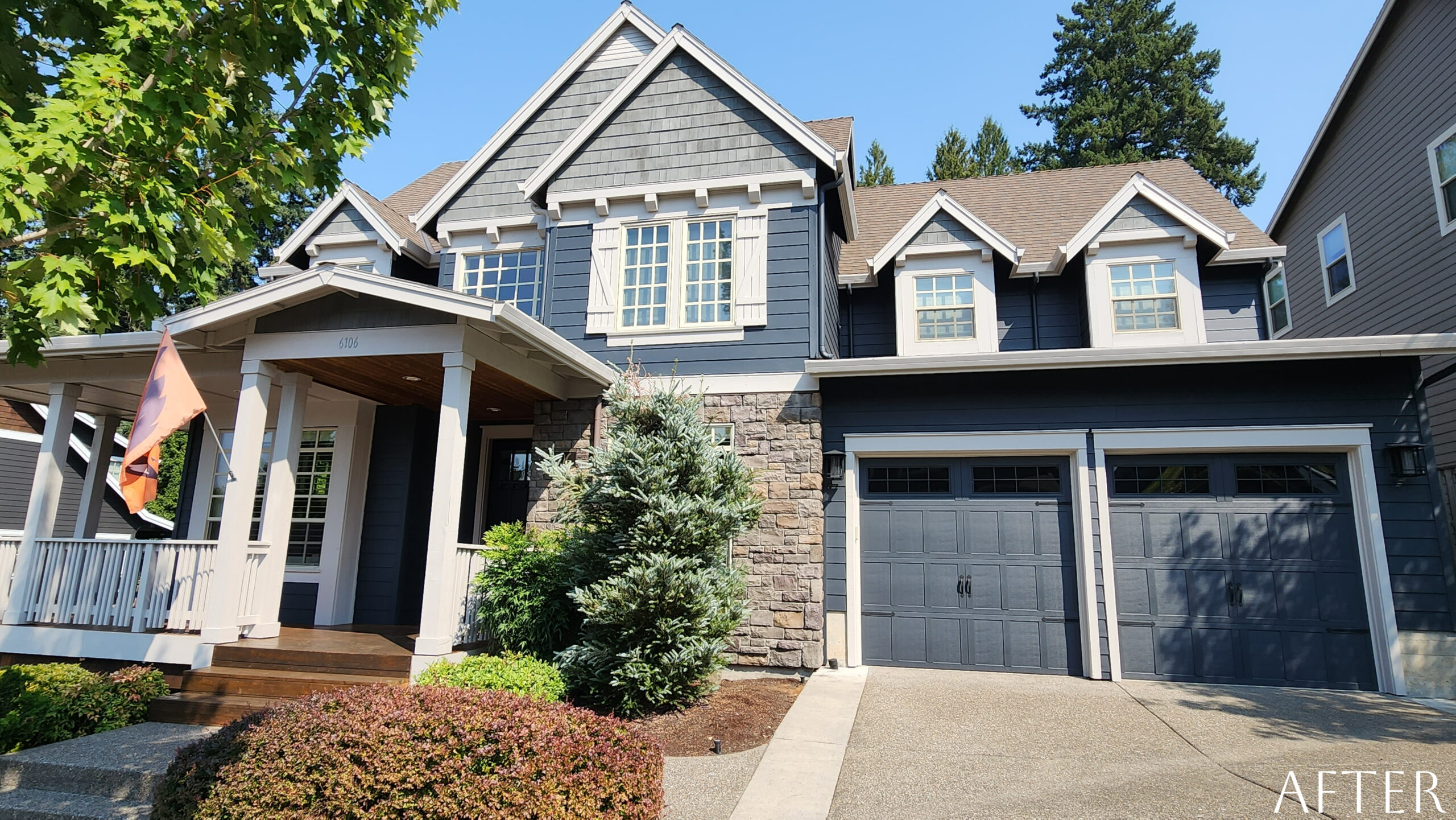 A home with a fresh transformation featuring gray siding and a garage door.