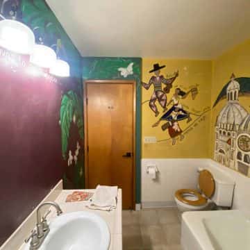 A bathroom with a colorful mural on the wall, painted by Pearl Painters.