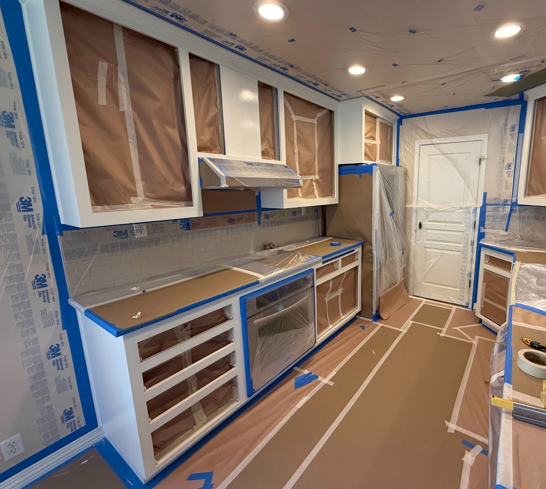 Kitchen in Portland being prepped for painting by Pearl Painters with surfaces taped and floor covered for protection.