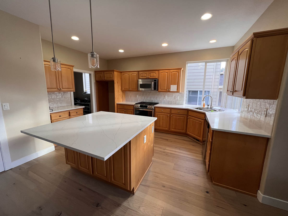 An empty kitchen with wood cabinets and white counter tops in need of a Cabinet Update.