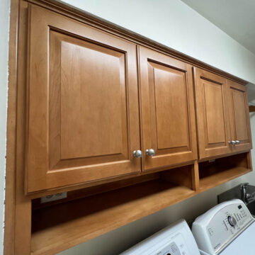 A laundry room with wooden cabinets and a washer and dryer.