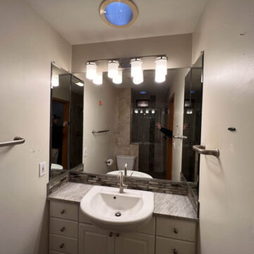 A bathroom with a sink, mirror, and lights.