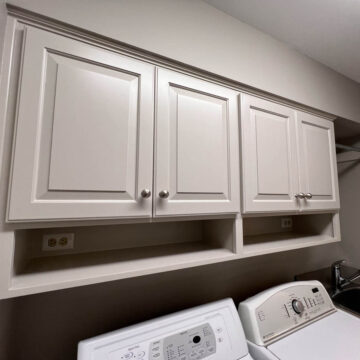 A laundry room with white cabinets and a washer and dryer.