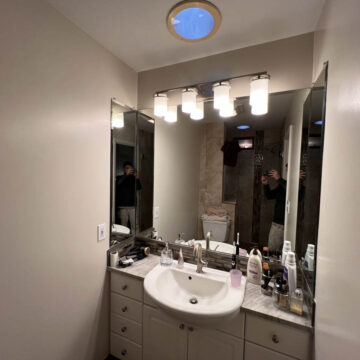 A bathroom with a sink, mirror, and lights.