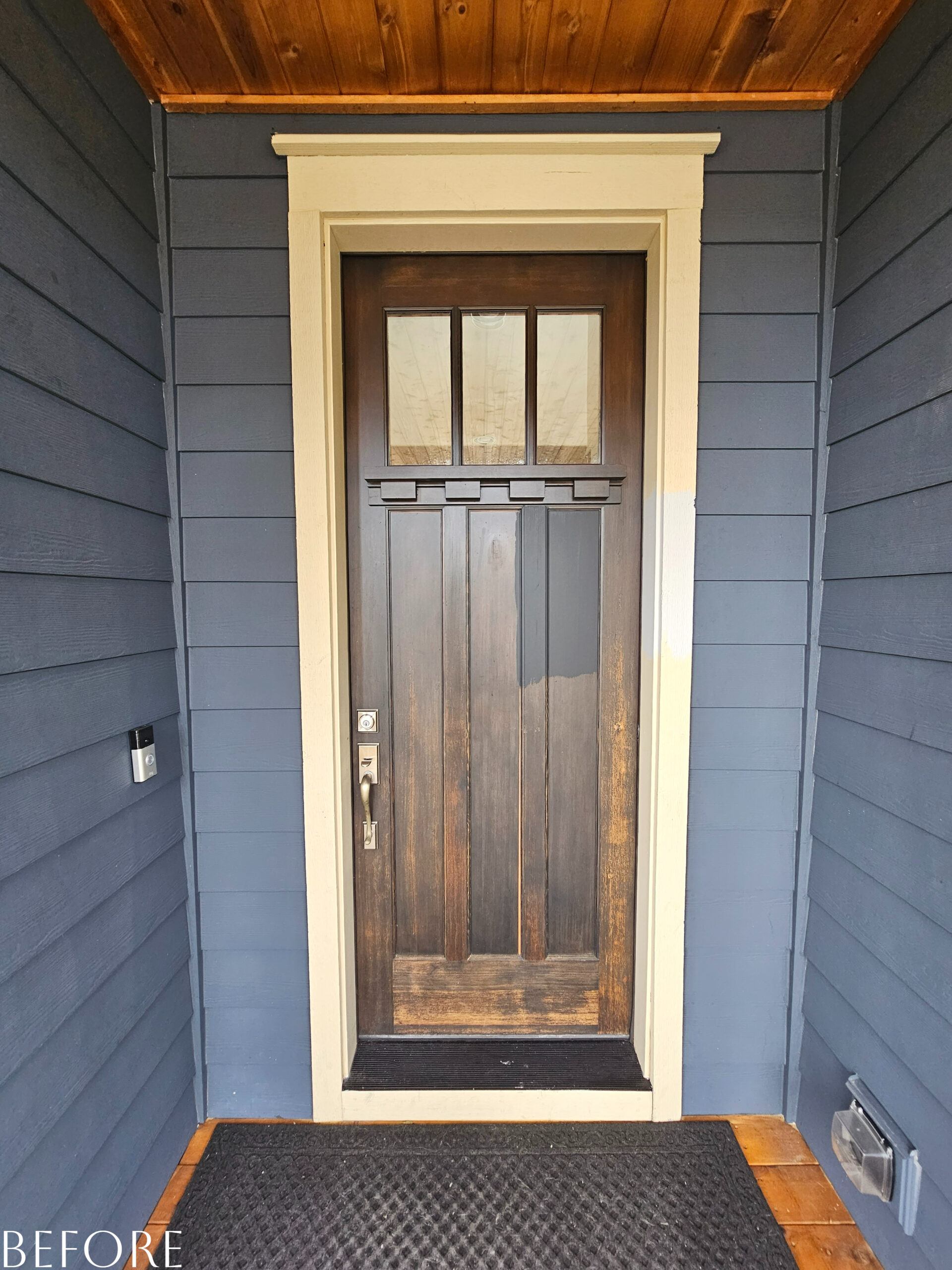 A Fresh front door with a black mat on it.