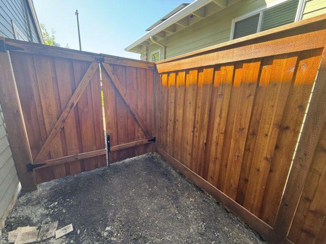 Wooden fence with double gate, metal hardware, installed by Smith in Portland; photo taken on a sunny July 2025 day by painter.