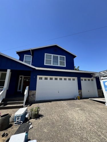 Jennings two-story house with blue siding, white trim, and three-car garage painted by Pearl Painters in July 2025.