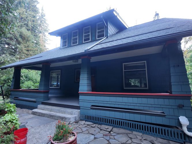 Blue two-story Gentry home with red trim and porch, painted by Pearl Painters in Portland; trees and plants surround walkway.