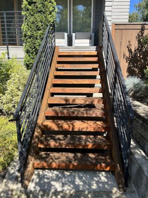 A wooden staircase with black railings leads to a glass door, greenery around. Painted by Pearl Painters, Portland, July 2025.