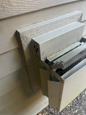 Damaged Feldon vent cover with bent panels and debris, on siding. Photo by Pearl Painters, Portland painters, July 2025.