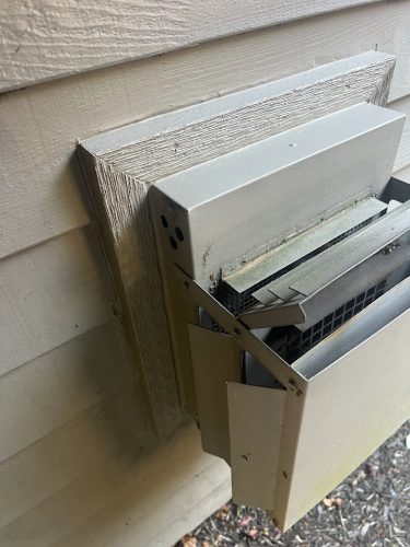 Damaged Feldon vent cover with bent panels and debris, on siding. Photo by Pearl Painters, Portland painters, July 2025.
