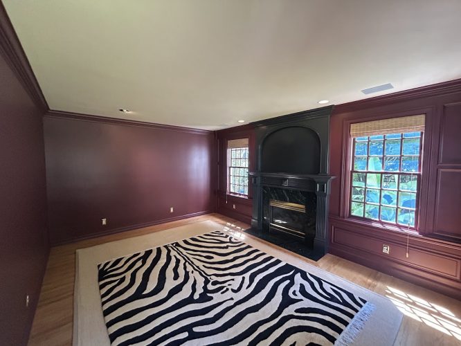 Room painted by Purcell, Pearl Painters, Portland: maroon walls, big windows, black fireplace, hardwood floors, zebra rug.