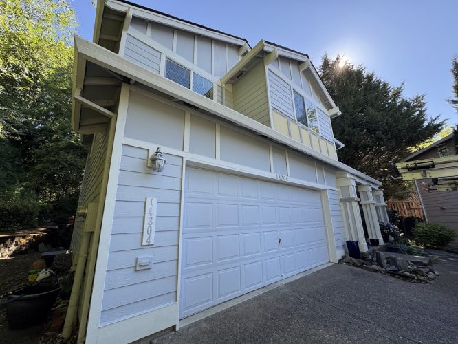 Painted by Pearl Painters in Portland: Two-story home, light gray siding, white trim, double garage, upsloping driveway.
