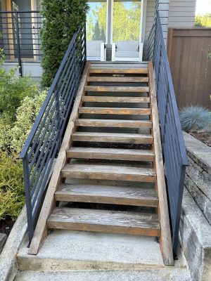 A Shimek wooden staircase with metal railings leads to a modern house entrance in Portland, painted by Pearl Painters.