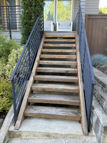 A Shimek wooden staircase with metal railings leads to a modern house entrance in Portland, painted by Pearl Painters.