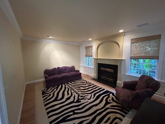 Painted by Pearl Painters in Portland, this living room has cream walls, a fireplace, windows, zebra rug, purple seating.