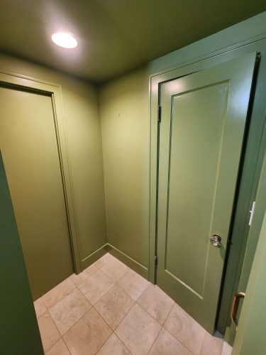 A painting by Pearl Painters, Portland: a Duc interior with light beige tiled floor, green walls and ceiling, and two closed green doors under a ceiling light.