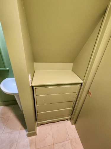 In April 2025, painter Duc from Pearl Painters in Portland painted a small built-in dresser with four drawers light green to match the bathroom’s beige tile floor.