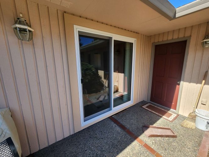 In April 2025, Pearl Painters painted this beige-paneled exterior with a sliding glass door and a red door in Portland. Visible items include a broom, welcome mat, and outdoor lights.