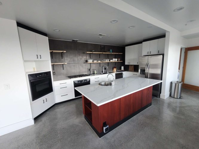 Modern kitchen painted by Pearl Painters in Portland features white Isadore cabinets, stainless steel appliances, open shelving, and a marble island on polished concrete floors.