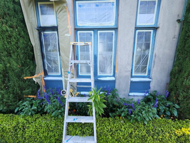Ladder in front of house, windows taped for painting by Pearl Painters, shrubs below. Photo by Ralph Barron, Portland, Aug 2025.