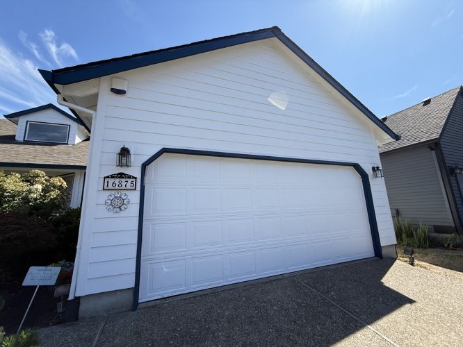 White two-car garage at 16875, Portland, with driveway. Painter ready for Pearl Painters’ July 2025 painting.