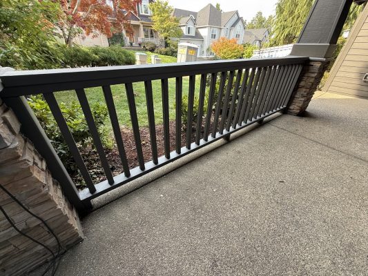 Montoya: Gray porch railing, stone pillar, yard with grass and trees. Painter or Pearl Painters could paint this scene in Portland.