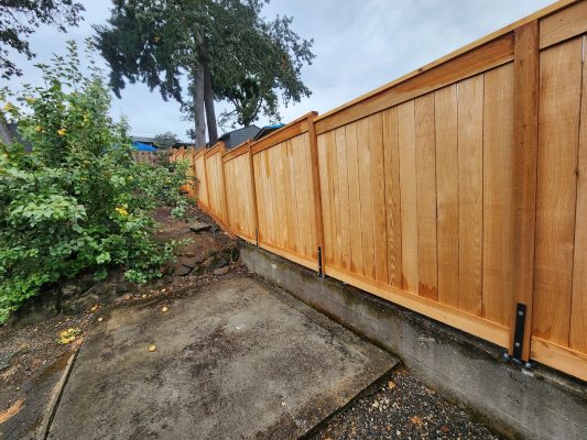 Wooden privacy fence on concrete base by a sloped yard in Arnold, painted by Pearl Painters on an overcast August 2025 day.