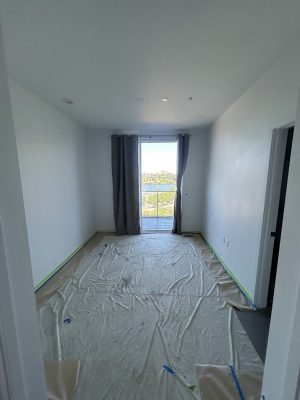 Empty room with white walls, plastic-covered floor for painting prep. Photo by Pearl Painters in Allen, July 2025.