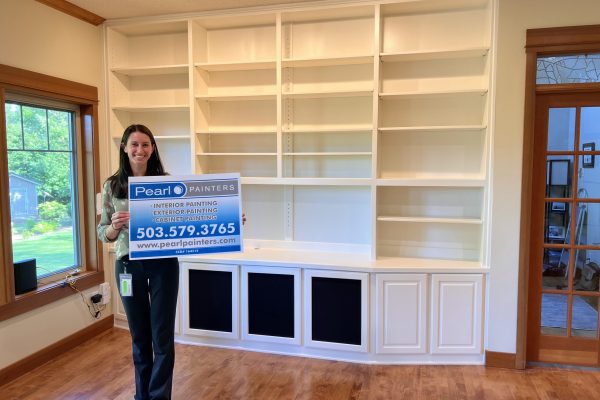 built-in cabinets repainted, with owner standing in front holding Pearl Painters sign