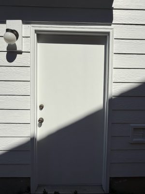 White door with two locks on white siding, exterior fixture left above. Painted by Pearl Painters, Nomura, July 2025.