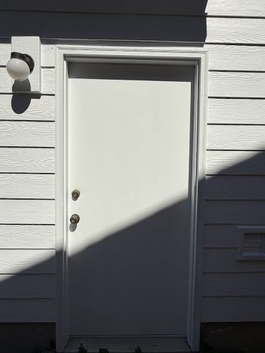 White door with two locks on white siding, exterior fixture left above. Painted by Pearl Painters, Nomura, July 2025.