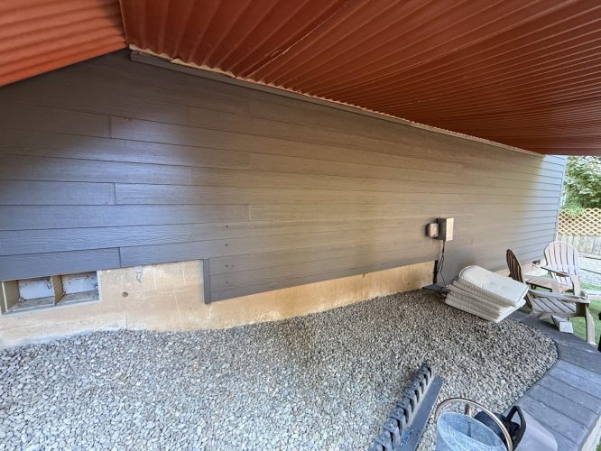 Dark wood siding by Montoya Exterior, gravel base, electrical box, boards; painting project finished Aug 2025. Not Portland.
