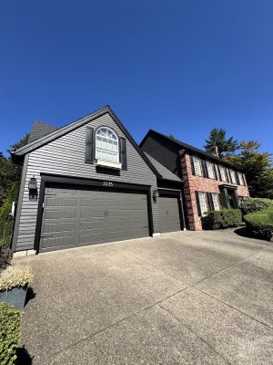 Gray two-story house in Portland with brick front, double garage, painted by Pearl Painters for Renee & Seamus Barron.