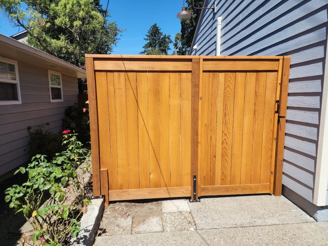 A painter from Pearl Painters in Arnold painted a wooden garden gate with black handle between houses near rose bushes.