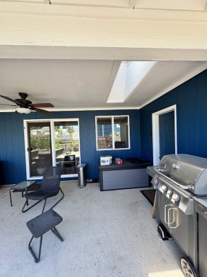 Covered patio in Portland with blue-painted walls, grill, chairs, fan. Painted by Pearl Painters. Sliding doors and window visible.