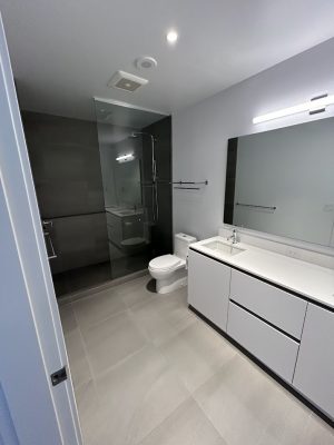 Modern bathroom in Allen with gray tile, glass shower, white vanity; fresh look ready for painting by Pearl Painters.