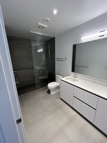 Modern bathroom in Allen with gray tile, glass shower, white vanity; fresh look ready for painting by Pearl Painters.