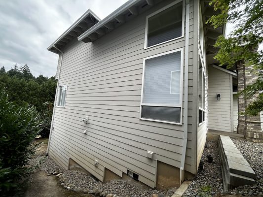 Beige two-story house with horizontal siding in Featherstone, painted by Pearl Painters, Portland painters. Greenery surrounds.
