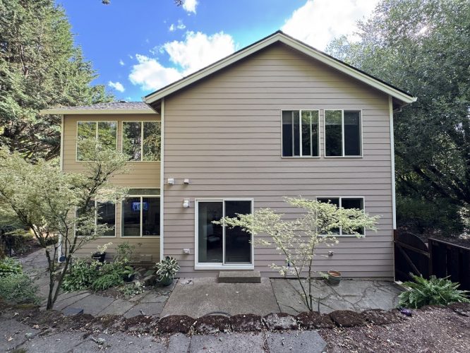 Two-story beige Anderson house in Portland with large windows, patio, and greenery. Painted by Pearl Painters.