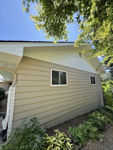 Beige house with white trim, two windows, sloped roof, greenery; painted by Pearl Painters in Cleveland, July 2025.