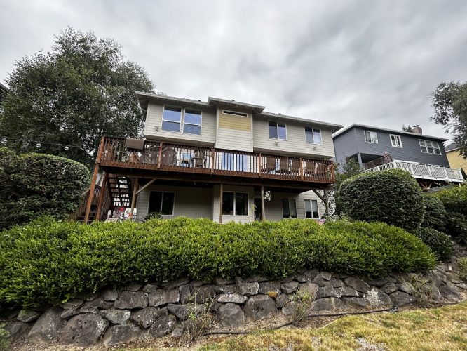 Featherstone house in Portland with deck and stone wall. Pearl Painters painting exterior in August 2025; cloudy sky.