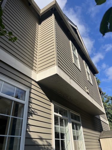 Pearl Painters painting a two-story Feldon home with beige siding, white trim, and windows in Portland under a sunny July sky.