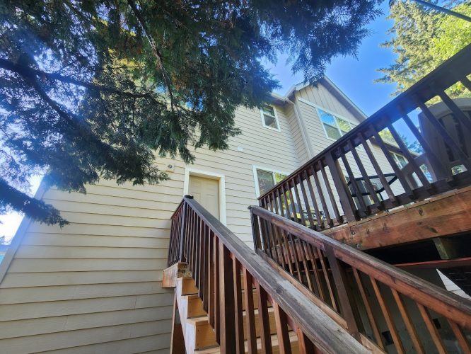 Beige Holley home exterior painted by Pearl Painters; wooden stairs, tree shade, blue sky in July 2025 near Portland.